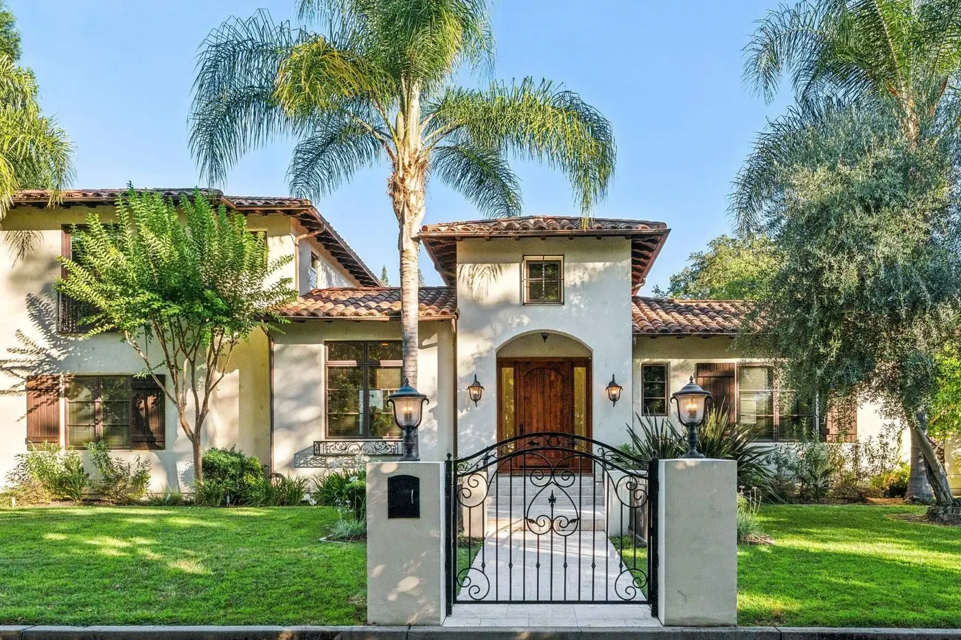 Spanish-style white house with red tile roof and palm trees